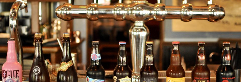 craft beer bottles lined up on a bar
