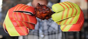 person holding chicken wing with keeper gloves