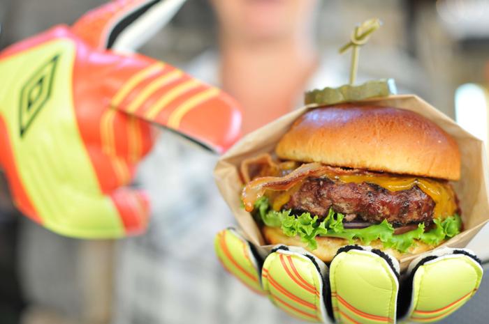 person holding a burger with soccer gloves