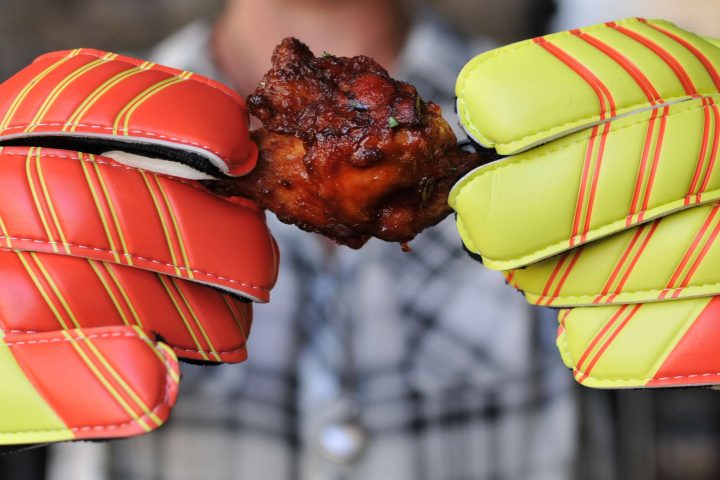 person holding chicken wing with keeper gloves